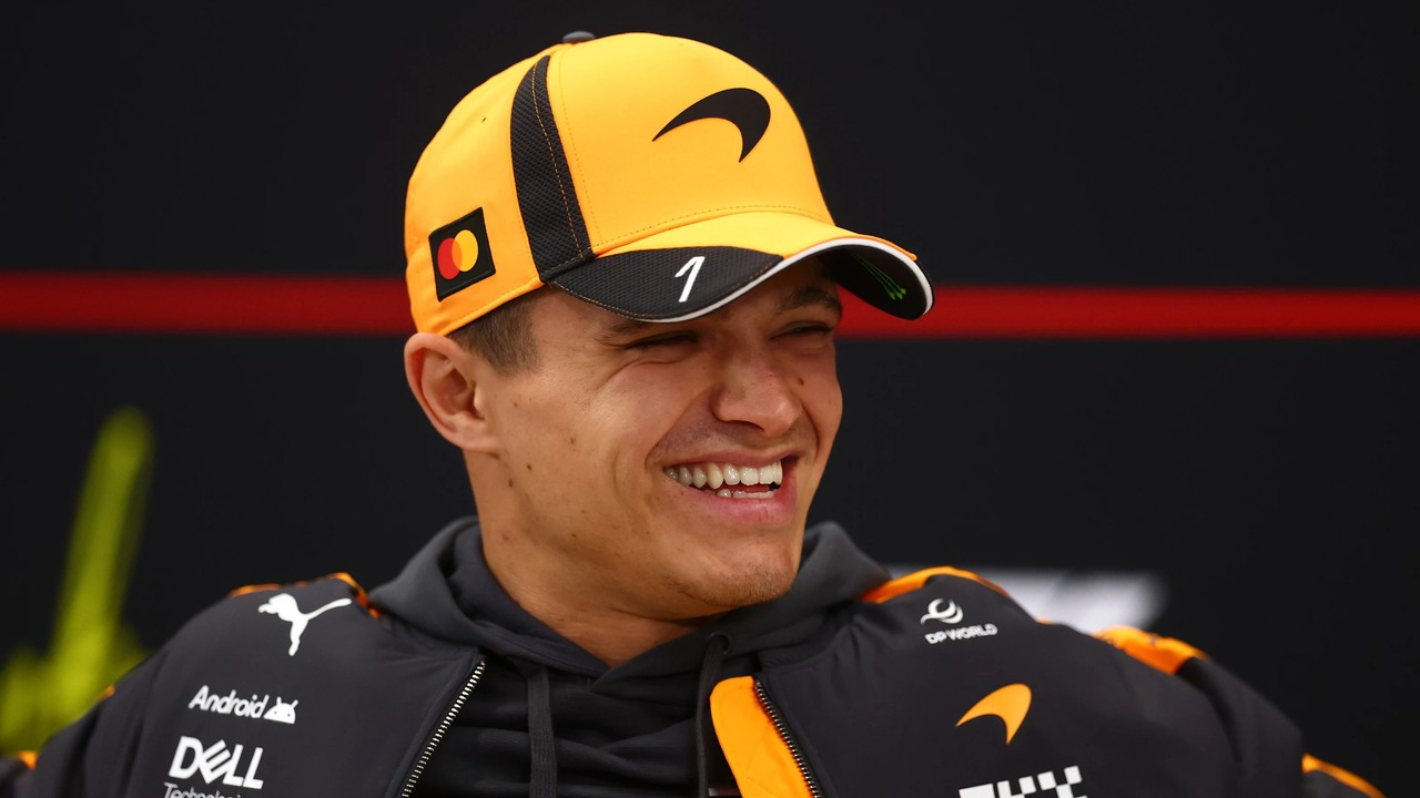 Lando Norris lächelt in einer McLaren-Kappe und einem Team-Shirt