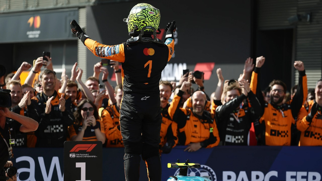 Lando Norris, kutlama yapan McLaren takımına doğru kollarını kaldırıyor.