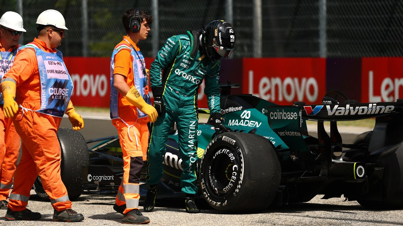 Aston Martin-Mechaniker stehen um ein Formula 1-Auto in der Garage