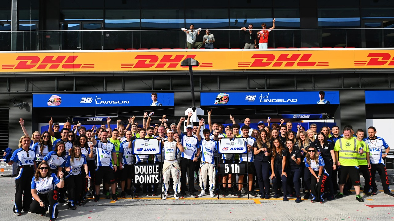 Personál a jezdci Racing Bulls pózují vedle boxové uličky